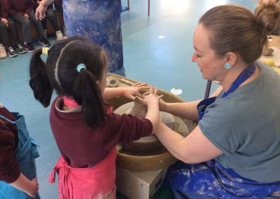 pottery teacher teaches a child how to make a pot